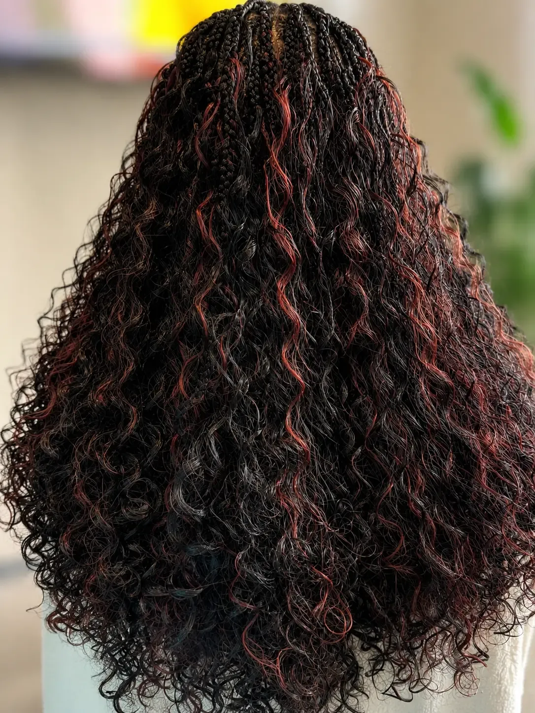 Long small boho knotless braids in natural black with auburn highlights and loose curly ends, back view