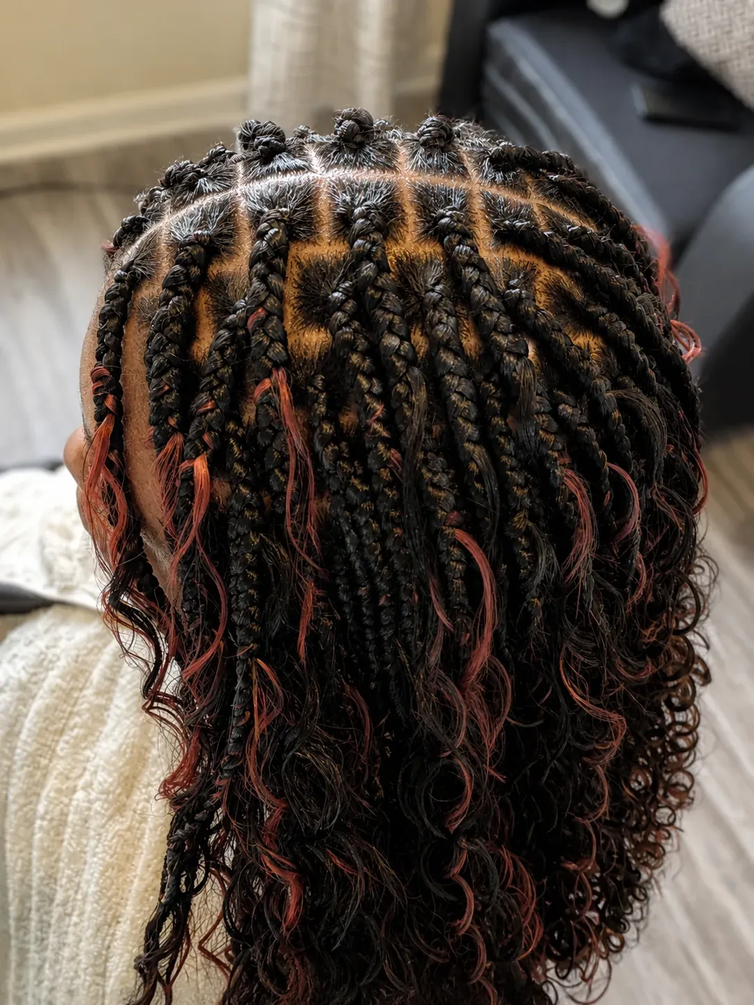 Neat boho knotless braids with copper accent pieces and curly ends, crown view