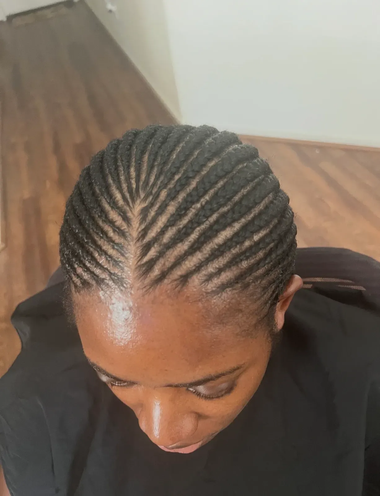 Feed-in cornrows braided close to the scalp and swept straight back in natural black, top-down view