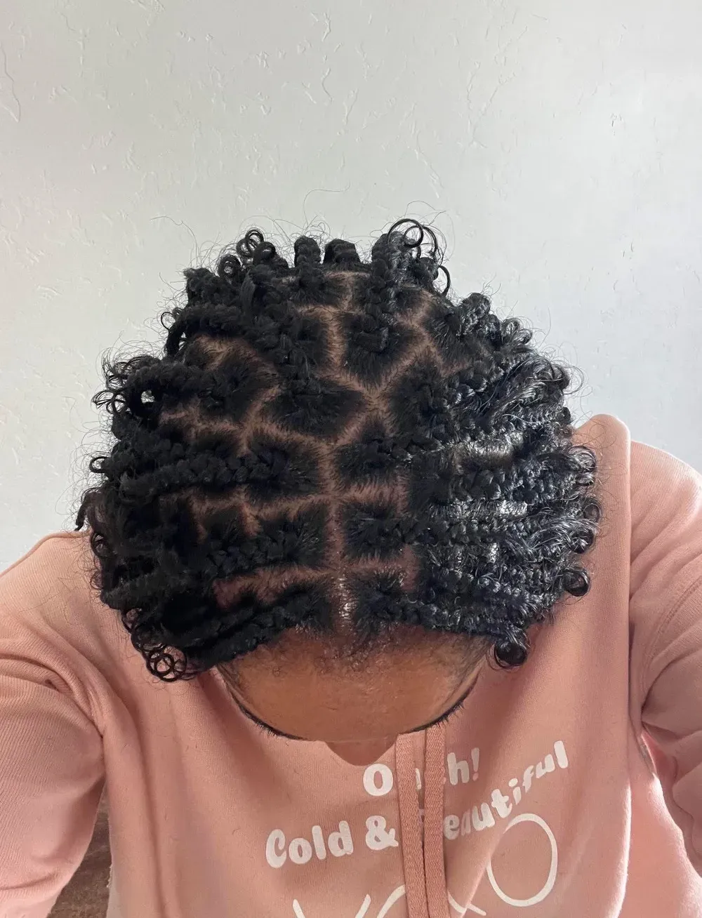 Short two-strand twists with curly ends and neat square parts, top-down view